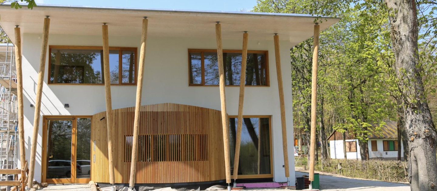 Das Forum Natura, ein modernes zweigeschossiges Gebäude mit weißer Fassade und vertikalen Holzstützen