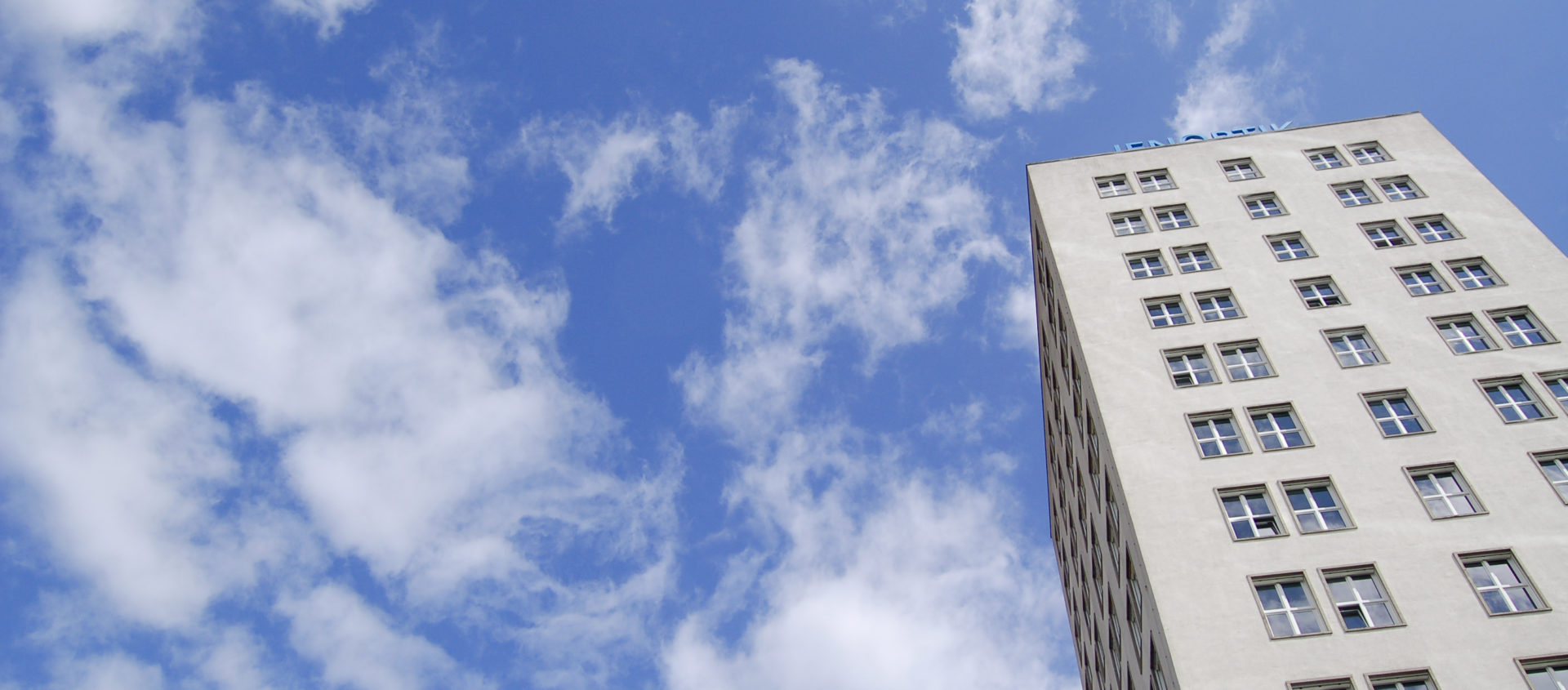 Blick von unten auf das Ernst-Abbe-Hochhaus in Jena vor blauem Himmel mit vereinzelten Wolken