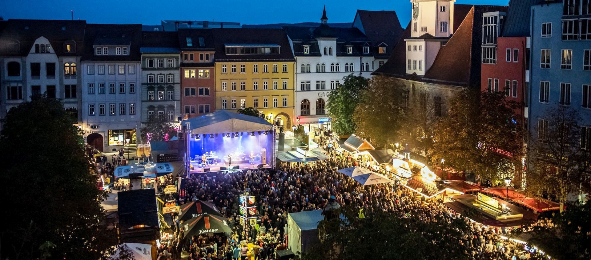 Abendliche Szene des Altstadtfests Jena mit großer Menschenmenge vor beleuchteter Bühne und historischen Gebäuden