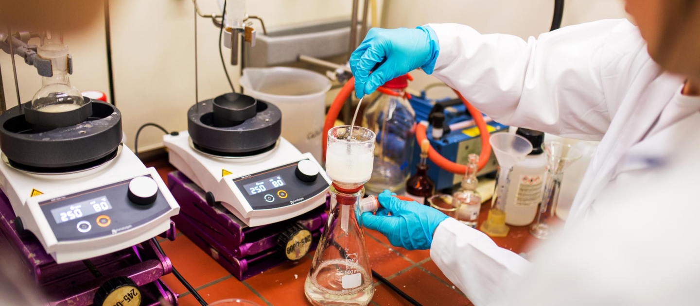 Person in weißem Laborkittel und blauen Handschuhen arbeitet mit Laborgeräten bei der Langen Nacht der Wissenschaften in Jena