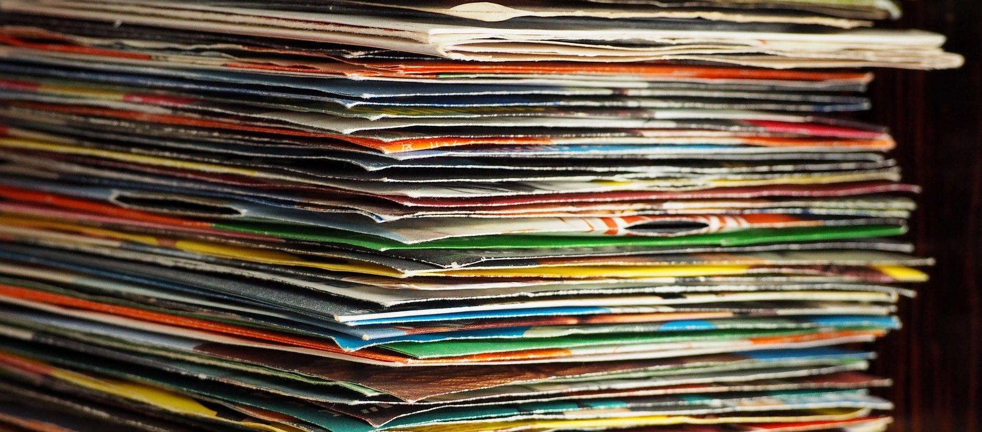 Nahaufnahme eines hohen Stapels von Schallplattenhüllen mit sichtbaren Gebrauchsspuren