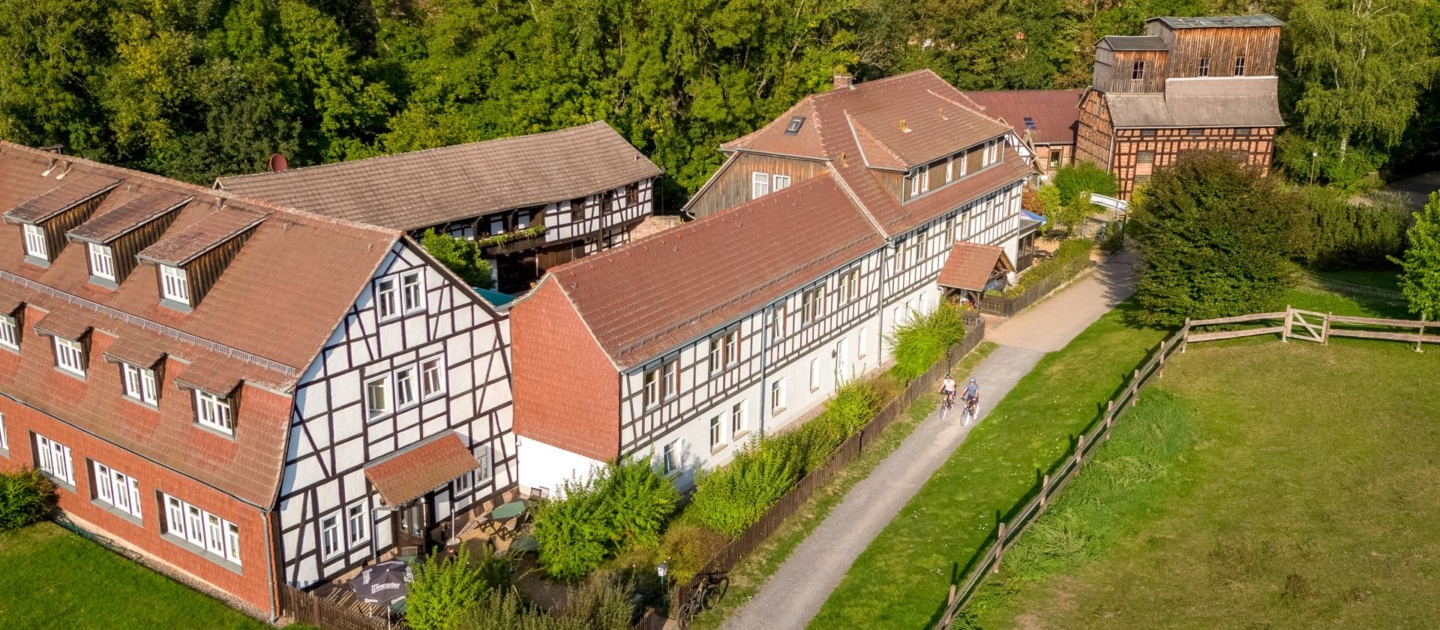 Luftaufnahme von Fachwerkhäusern entlang des Radweges Thüringer Städtekette mit angrenzendem Grünland und Wald im Hintergrund