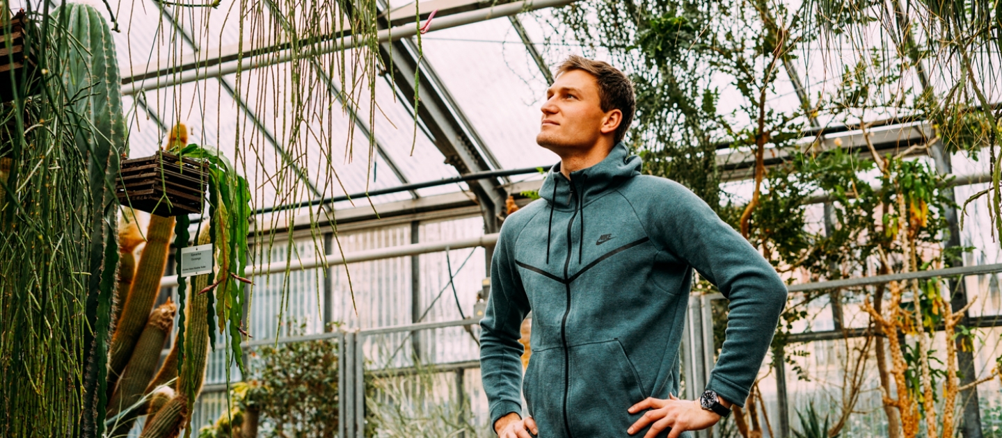 Ein Mann steht in einem Gewächshaus des Botanischen Gartens in Jena, umgeben von hängenden und kletternden Pflanzen.