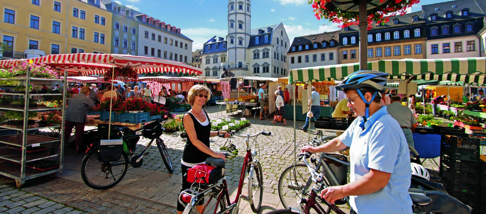 Marktplatz in Gera mit Marktständen und zwei Radfahrern im Vordergrund