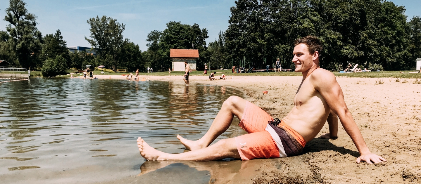 ein Mann sitzt in Badekleidung am Ufer des Schleichersees in Jena