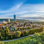 Panorama der Stadt Jena mit der Saale, grünen Uferbereichen und der aufgehenden Sonne am Horizont