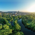 Panoramablick auf die Saaleaue in Jena mit Fluss, grünen Wiesen und Stadt im Hintergrund bei Sonnenaufgang