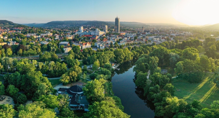Panoramablick auf die Saaleaue in Jena mit Fluss, grünen Wiesen und Stadt im Hintergrund bei Sonnenaufgang