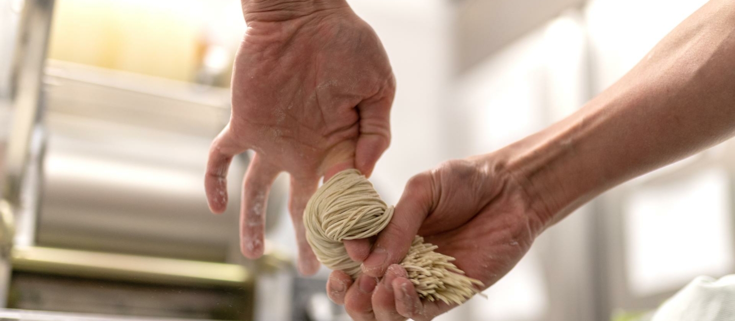 Hände, die frische Ramen-Nudeln formen