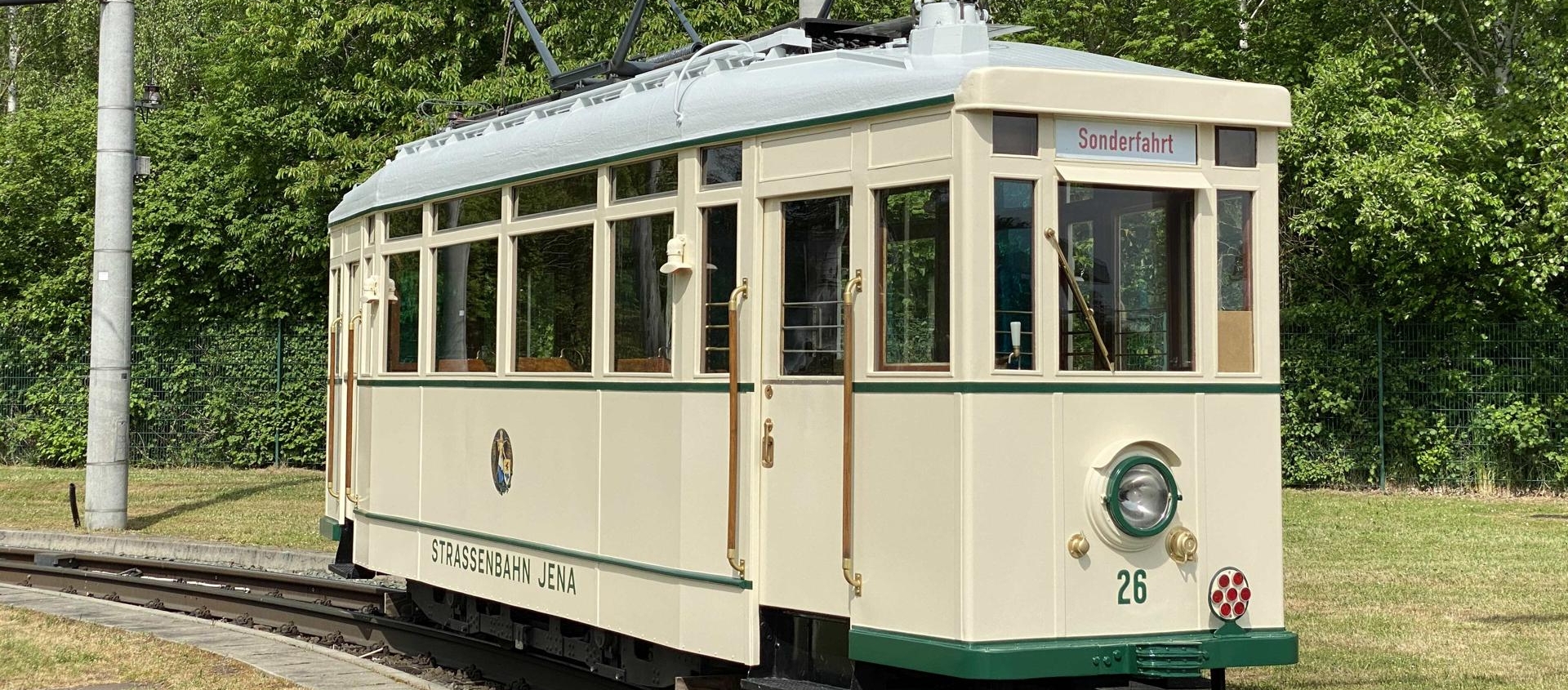 Historische Straßenbahn Triebwagen 26 der Jenaer Nahverkehrsgesellschaft auf Sonderfahrt auf Gleis in grünem Park