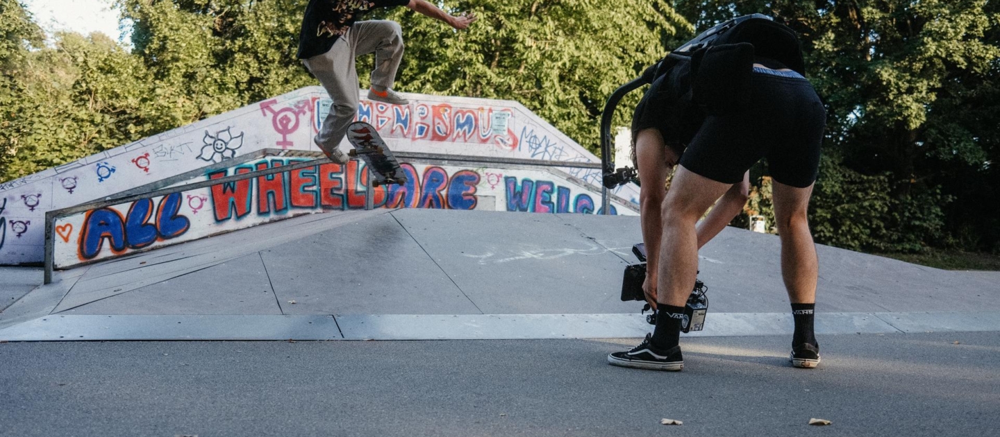 Skater führt Trick auf Rampe mit Graffiti in Jena aus, während Kameramann nah filmt
