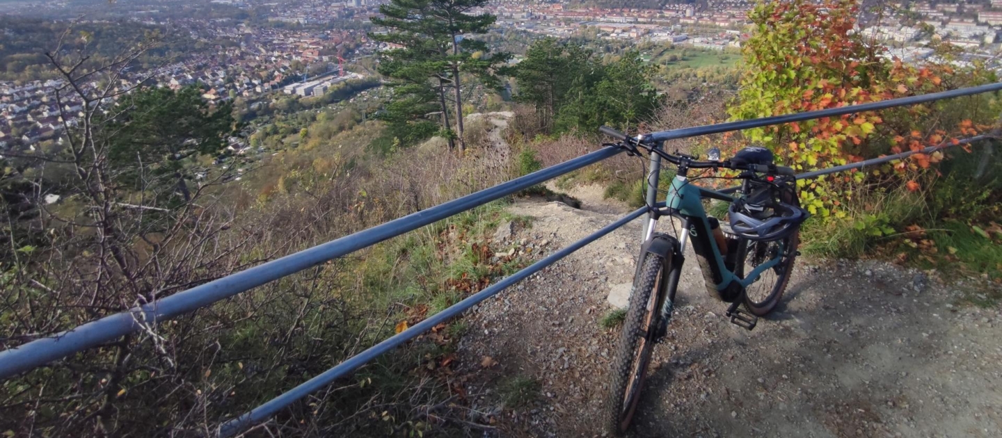 Mountainbike an Geländer auf Aussichtspunkt mit Blick auf Jena und umliegende Landschaft unter blauem Himmel