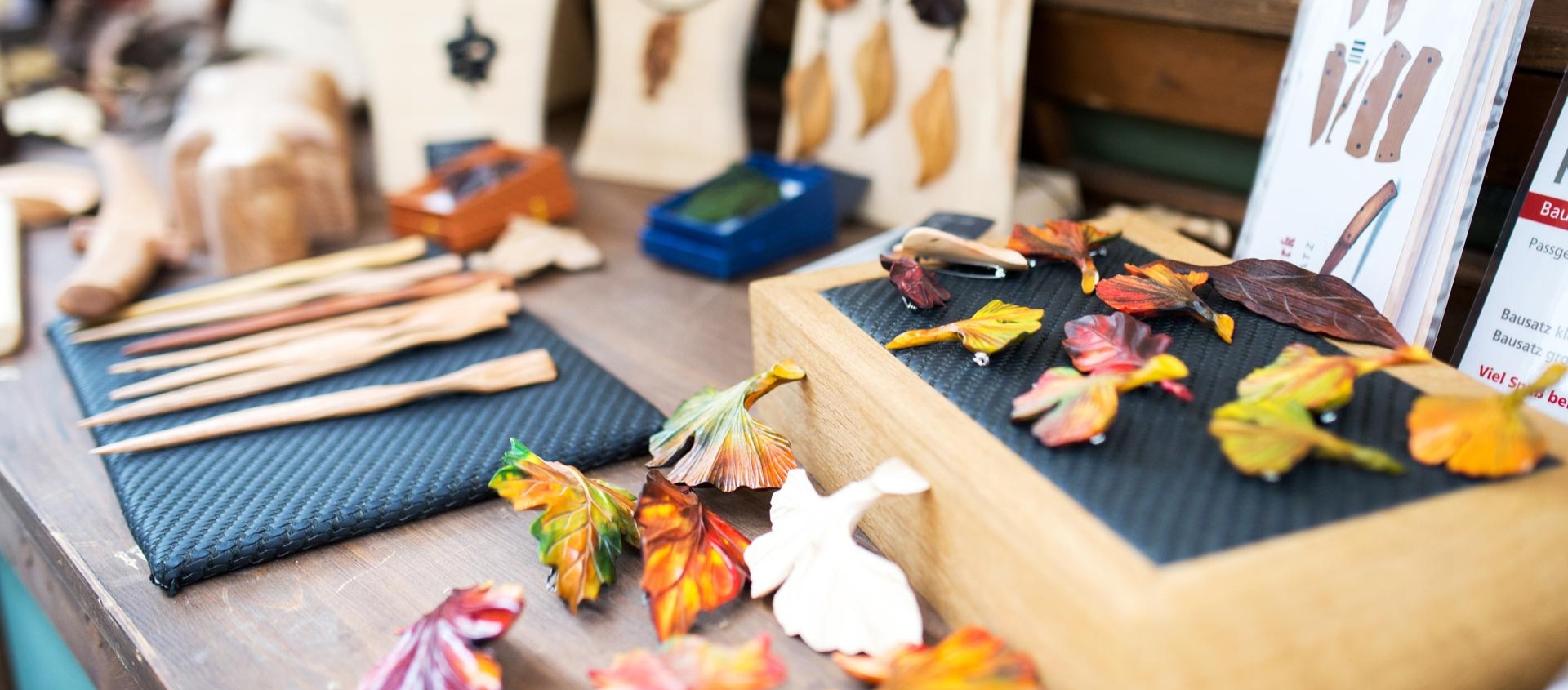 Bunte Keramikblätter und handgefertigte Holzstäbe auf einem Tisch beim Töpfermarkt in Jena