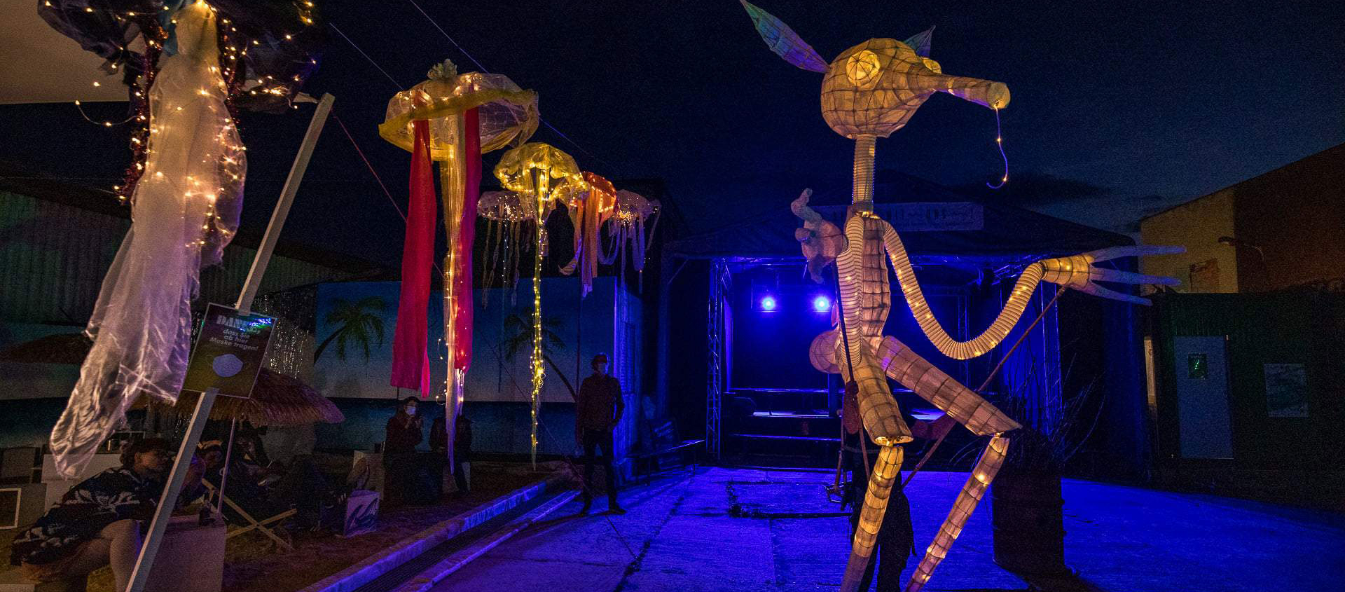 Leuchtende, skurrile Figuren aus Papier und Licht auf einer Bühne im Kulturschlachthof Jena bei Nacht