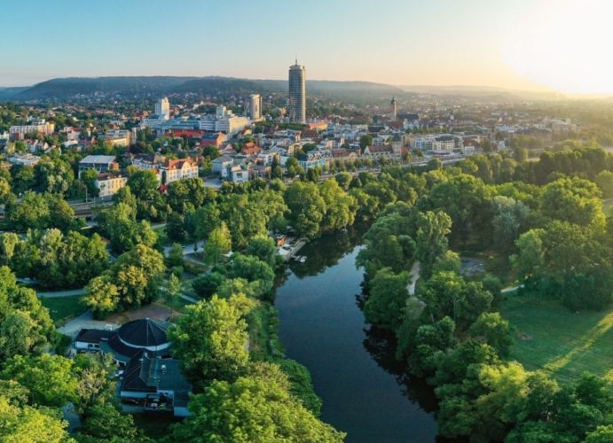 Panoramablick auf die Saaleaue in Jena mit Fluss, grünen Wiesen und Stadt im Hintergrund bei Sonnenaufgang