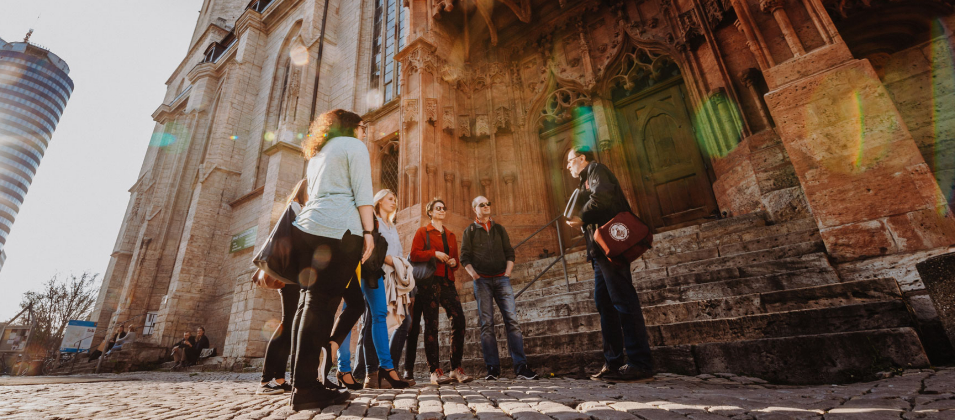 Gruppe von Menschen bei einer Stadtführung vor der Stadtkirche in Jena