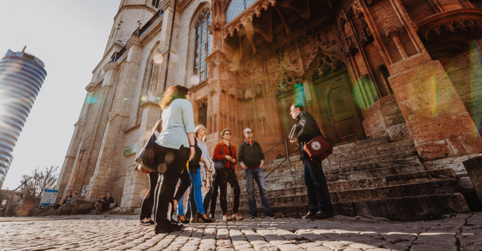 Gruppe von Menschen bei einer Stadtführung vor der Stadtkirche in Jena